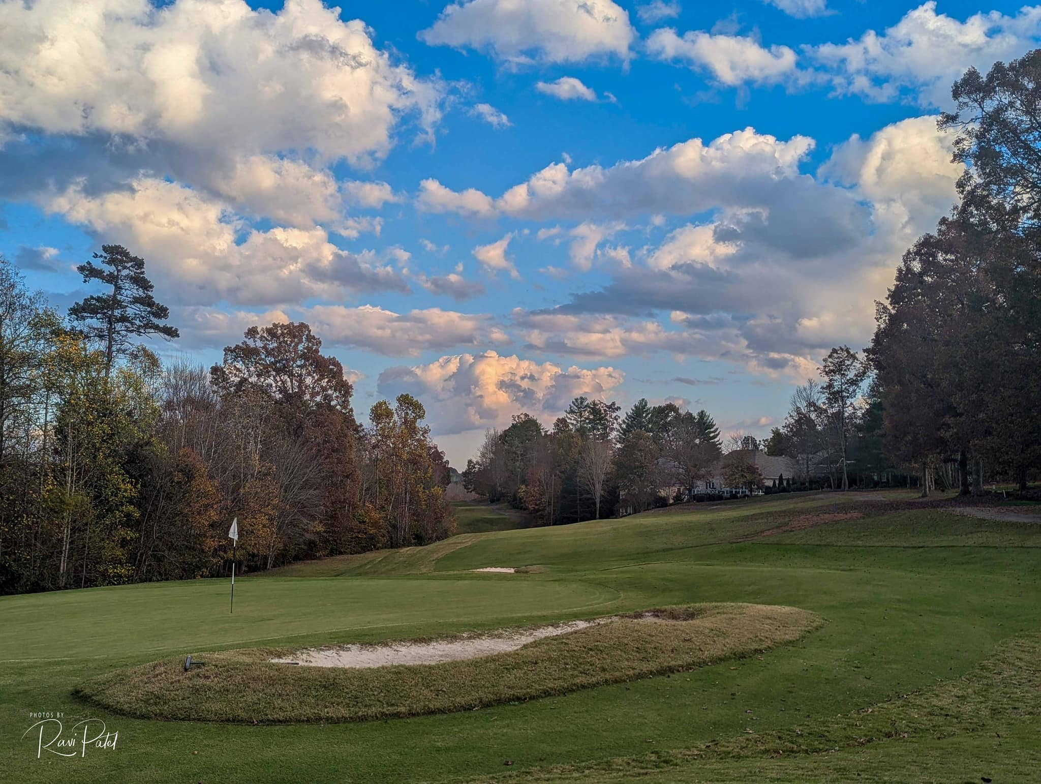 View of golf course beneath clouds in blue sky 